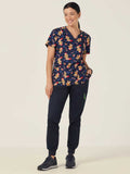 Woman wearing a navy scrub top with christmas pattern